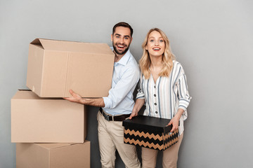 Wall Mural - Photo of nice caucasian couple in casual clothing looking at camera and carrying cardboard boxes