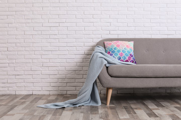 Sticker - Minimalist living room interior with cozy sofa, pillow and plaid near brick wall. Space for text