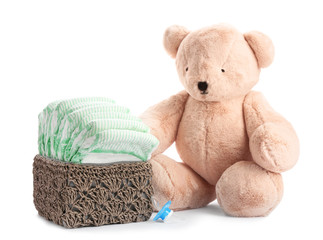 Wall Mural - basket with diapers, pacifier and teddy bear on white background. baby accessories