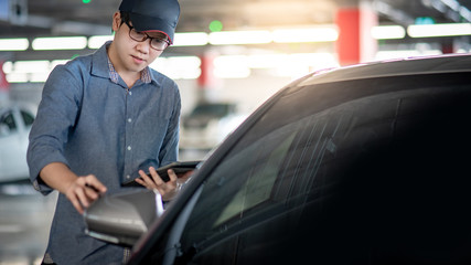 Wall Mural - Young Asian auto mechanic holding digital tablet checking car wing mirror. Mechanical maintenance engineer working in automotive industry. Automobile servicing and repair concept