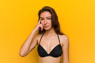 Wall Mural - Young european woman wearing bikini showing a disappointment gesture with forefinger.