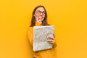 Young pretty caucasian woman relaxed thinking about something looking at a copy space. She is holding a map.