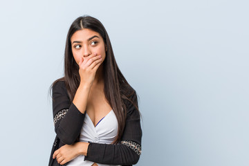 Young natural and pretty arab woman thoughtful looking to a copy space covering mouth with hand.