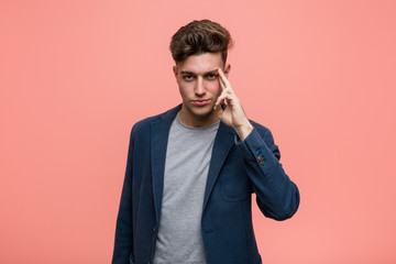 Young business natural man pointing temple with finger, thinking, focused on a task.