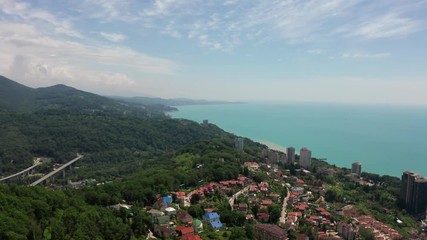 Wall Mural - Aerial video shooting. Flying over a residential area. The city resort of Sochi. Black sea coast. Green forest and mountains by the sea.