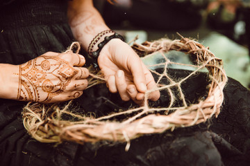 girl with mehendi weaves a dream catcher in the forest. ethnics.. hand made