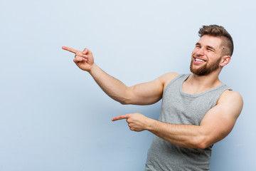 Wall Mural - Young handsome fitness man excited pointing with forefingers away.