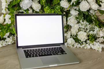 Home office desk with blank screen laptop, beautiful roses and eucalyptus bouquet, Blog, website or social media concept