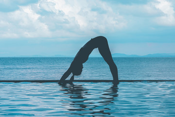 Wall Mural - silhouette woman practice yoga Downward Facing dog or yoga Adho Mukha Svanasana pose meditation summer vacation on the pool,Travel in tropical beach Thailand,vacations and relaxation Concept