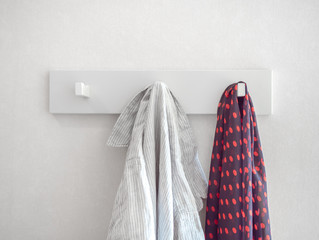 White relaxed striped shirt and red polka dot pattern scarf hanging on white hanger on white wall