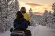 2 people riding on a snowmobile through the wilds of Lapland
