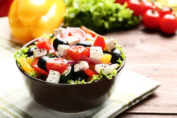 Vegetable salad in bowl with napkin on wooden table