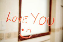 Confession Of Love And Smiley Face Written With Red Lipstick On The Mirror In Bathroom