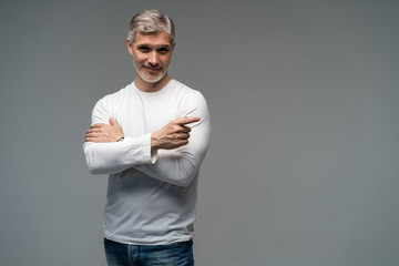 Handsome middle age senior man presenting and pointing with palm of hand looking at the camera over gray background.