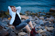 © soleg - fashionable girl dressed in white jacket and wide trousers posing near sea in the evening