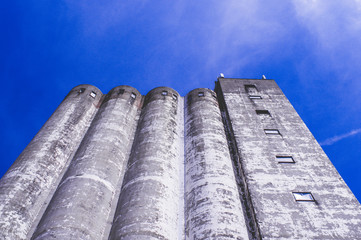 Old weathered building silo of a former paint store with well-worn colors and a red rope