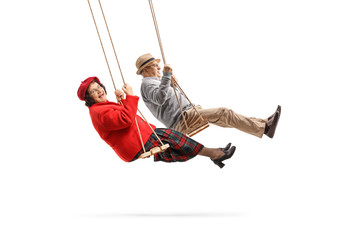 Canvas Print - Senior husband and wife looking at the camera and swinging on swings