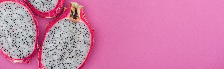 Wall Mural - panoramic shot of exotic ripe dragon fruit halves on pink background