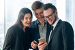 © golubovy - Information technology. Modern office lifestyle. Young colleagues laughing at fun content in guy smartphone.