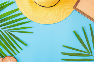 summer blue banner with yellow hat ,sunglasses,seashell,frame and palm leaf on blue background top view.