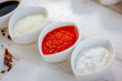 Different dips and sauces - red, white and black over white table.