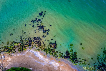 Wall Mural - Aerial drone view of crystal clear lagoon sea water surface with rocks and seagulls