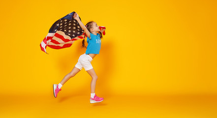 happy child girl with flag of   United States of America USA on yellow   background.