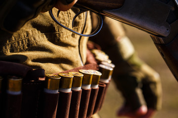 Ammunition with a gun, cartridges. Hunter man. Man is charging a hunting rifle. The man is on the hunt. Ammunition bullet. Male hunter ready to hunt with hunting rifle. Close up ammunition