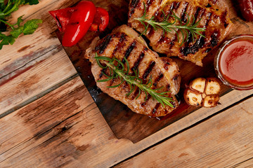 Wall Mural - Grilled meat. Steak pork grill on wooden cutting board  on  rustic background  Top view. Flat lay.