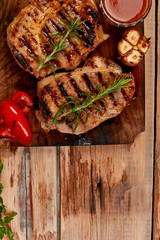 Wall Mural - Grilled meat. Steak pork grill on wooden cutting board  on  rustic background  Top view. Flat lay.