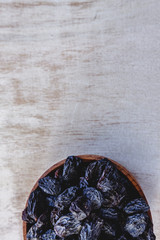 Wall Mural - Dark blue raisins in a wooden bowl on a bright white background. Close-up. Insulated.