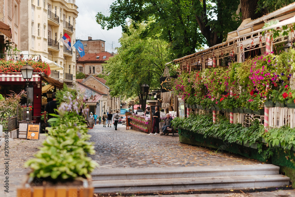 Obraz na płótnie Belgrade, Serbia - June 16, 2018. Flowers in pots on historic place Skadarlija with trees, cafes, cobbled lanes and alleys in downtown. Bohemian street with bars and restaurants. w salonie