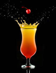 Wall Mural - cherry falling into a splashing tequila sunrise isolated on black