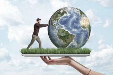 Crop side view of woman's hand holding digital tablet with green grass growing on screen and little man pushing planet Earth on top.