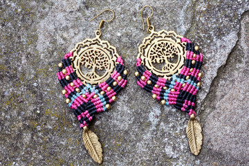 Wall Mural - Metal macrame earrings on rocky background