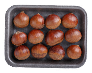 Wall Mural - Fresh raw edible sweet chestnuts on black foam food tray isolated on white. Top view. Close-up.