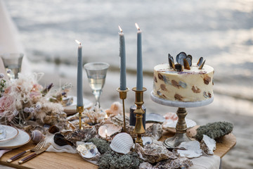 Sea wedding decor on the coast. Wedding cake and flowers at the event.