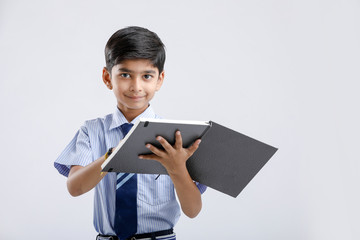 Wall Mural - Cute little Indian/Asian school boy showing note book over white background