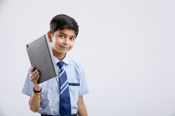 Wall Mural - Cute little Indian/Asian school boy showing note book over white background