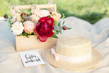 Straw hats lay on a white picnic blanket at green lawn bright summer day