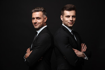 Sticker - Handsome two adult business men posing isolated over black wall background.