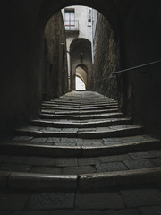 Wall Mural - Low angle urban view of tunnel with streets going up to the light in old medieval town from Italy