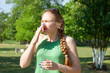 © biggur - Young woman with allergy during sunny day is wiping her nose.