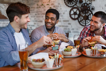 Friends Eating Burgers And Enjoying Beer, Sitting In Bar