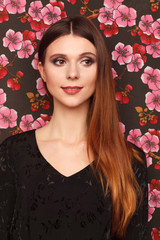 Wall Mural - Portrait of a beautiful woman in a black dress. Background from a fabric in drawing flowers