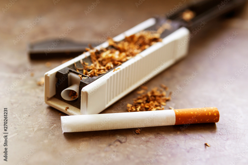 The machine for stuffing cigarettes with tobacco. Empty sighety. Rossypany  tobacco on the table. Homemade cigarette production Stock Photo