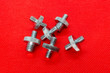 Metal double-sided Nickel-plated screws on a red background
