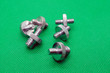 Metal double-sided Nickel-plated screws on a green background