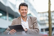 © Westend61 - Portrait of smiling businessman using tablet outdoors