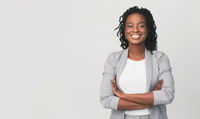 successful african businesswoman with arms crossed, grey background